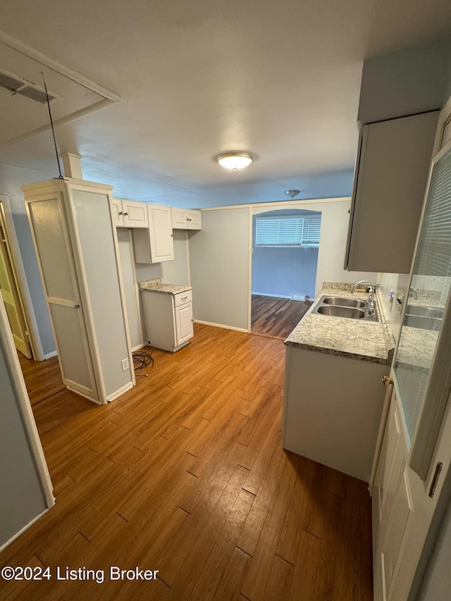 kitchen featuring white cabinets, wood-type flooring, and sink