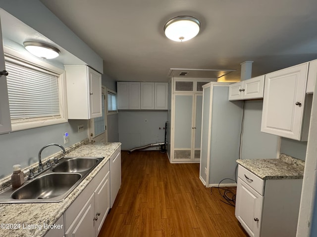 kitchen with dark wood-type flooring, white cabinets, sink, stainless steel dishwasher, and light stone countertops