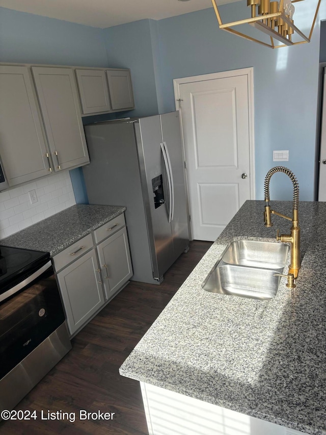 kitchen with gray cabinetry, sink, dark hardwood / wood-style floors, appliances with stainless steel finishes, and light stone counters