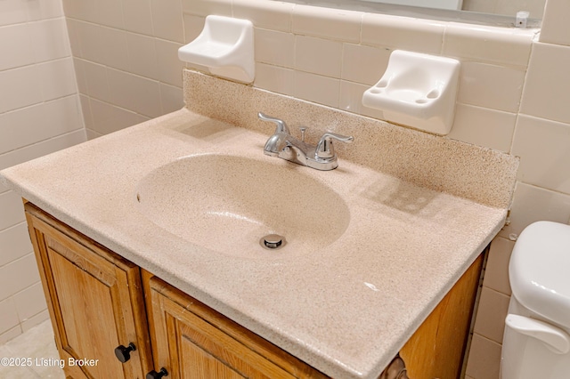 bathroom with tasteful backsplash, vanity, toilet, and tile walls