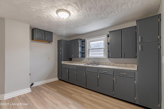 kitchen with light hardwood / wood-style flooring, sink, and gray cabinets