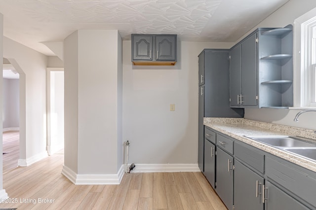 kitchen with light wood-type flooring, sink, and gray cabinetry