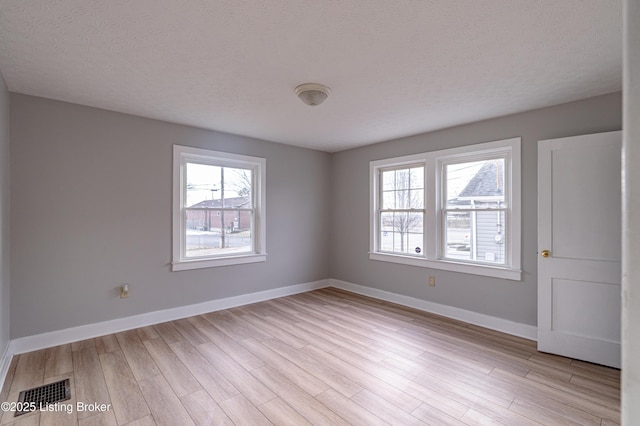 unfurnished room with light hardwood / wood-style flooring and a textured ceiling