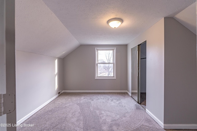 bonus room with lofted ceiling, carpet floors, and a textured ceiling