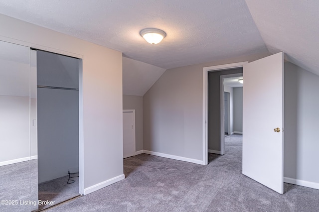 additional living space with lofted ceiling, carpet floors, and a textured ceiling