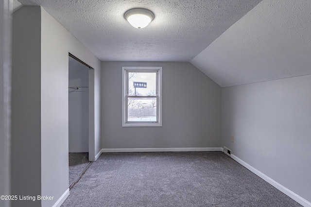 additional living space featuring carpet, lofted ceiling, and a textured ceiling