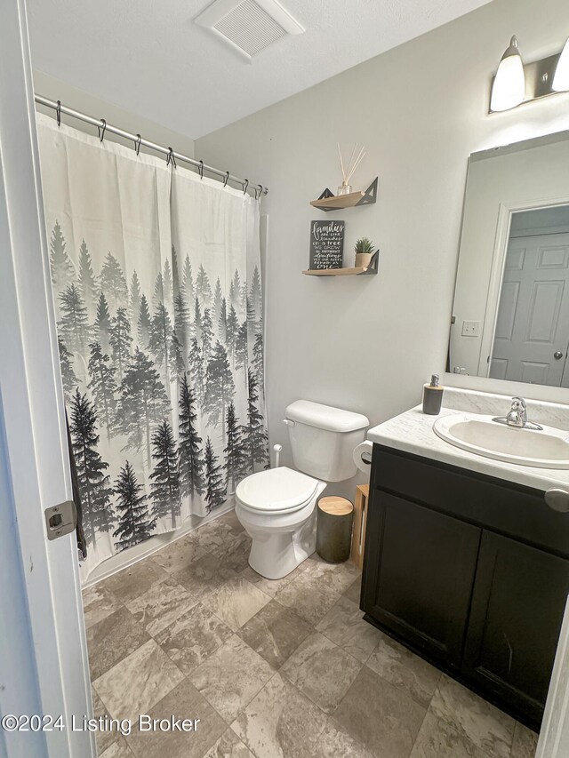 bathroom featuring a shower with shower curtain, vanity, and toilet