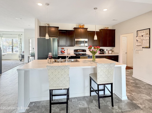 kitchen featuring a breakfast bar, stainless steel appliances, a kitchen island with sink, sink, and pendant lighting