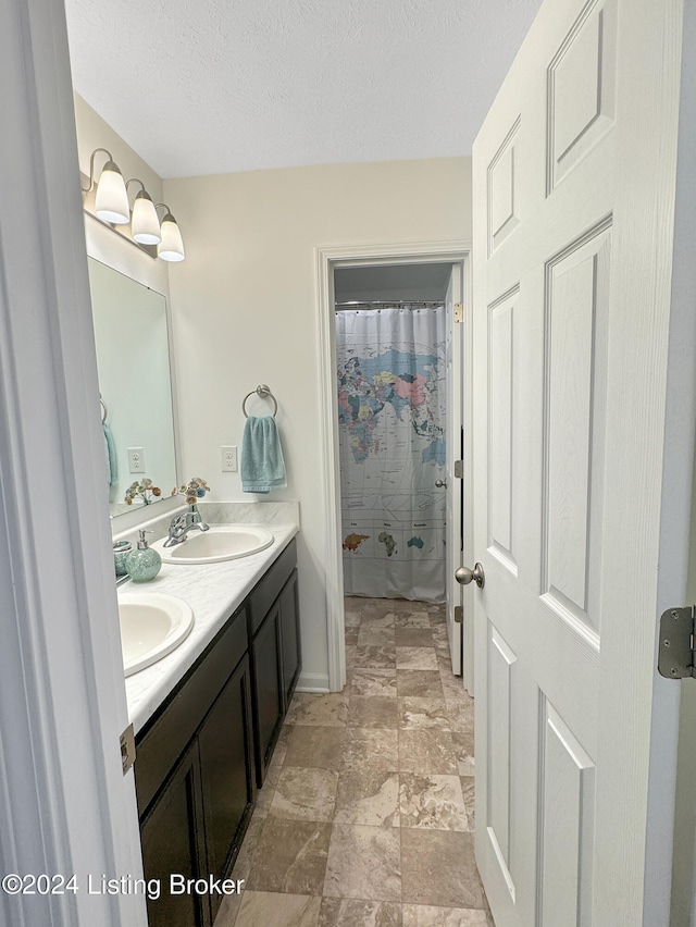 bathroom with vanity, a shower with shower curtain, and a textured ceiling