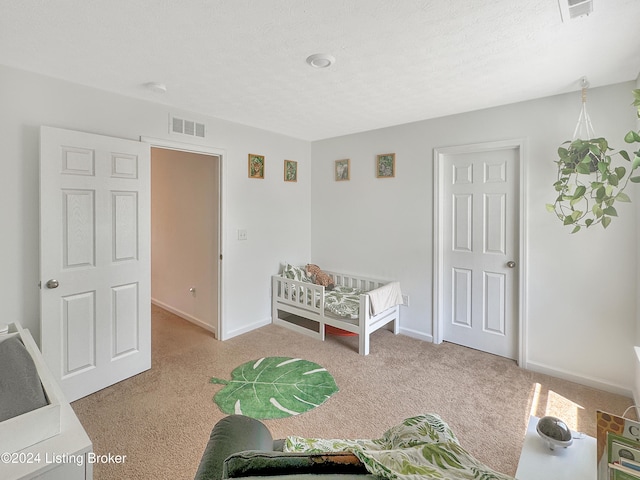 carpeted bedroom with a crib and a textured ceiling