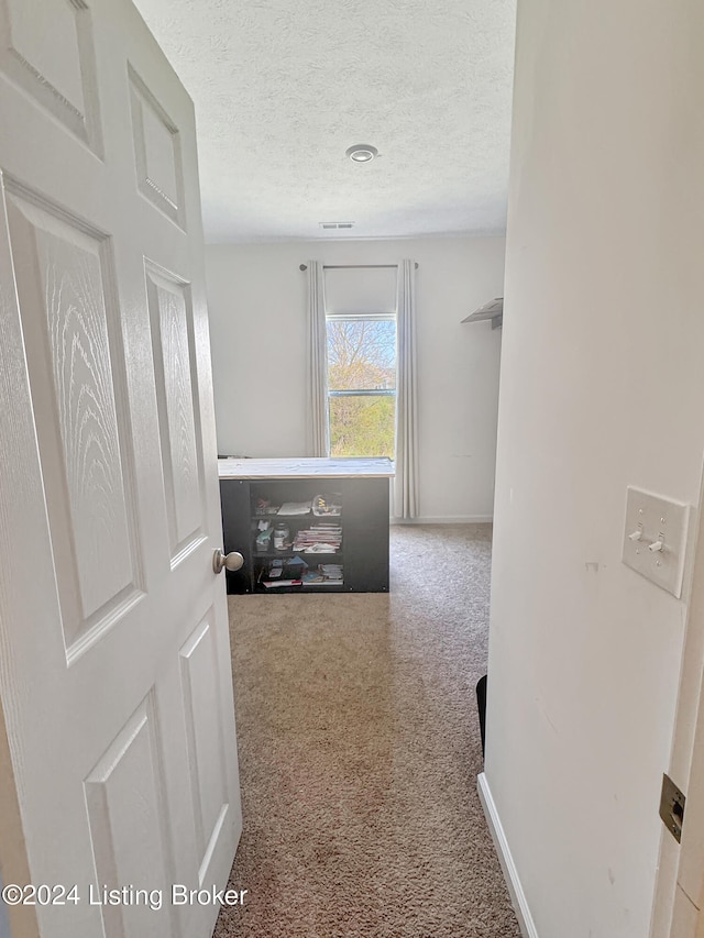 hall with carpet floors and a textured ceiling