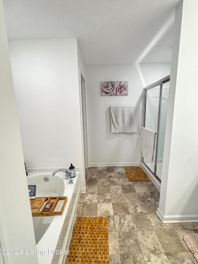 bathroom with a textured ceiling and separate shower and tub