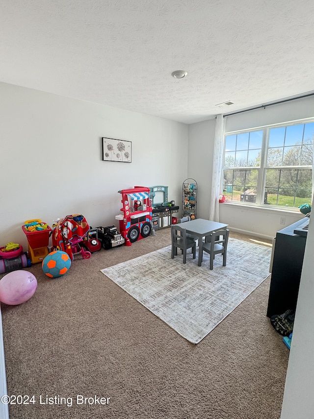 playroom featuring carpet and a textured ceiling