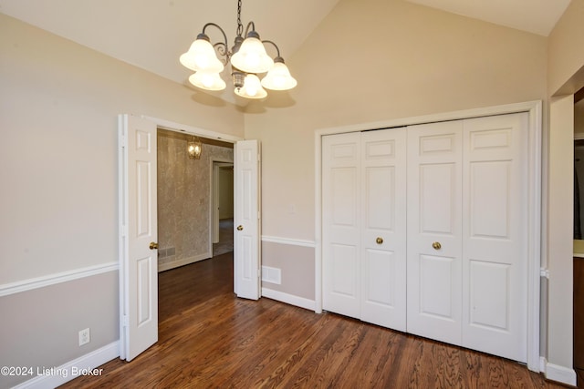 unfurnished bedroom with a chandelier, high vaulted ceiling, a closet, and dark wood-type flooring