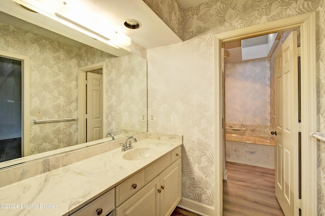 bathroom with hardwood / wood-style flooring, vanity, and a tub