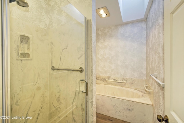 bathroom featuring a skylight, hardwood / wood-style floors, and plus walk in shower