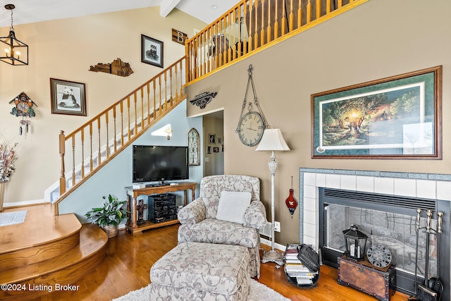 living room featuring beamed ceiling, hardwood / wood-style floors, high vaulted ceiling, and a tile fireplace