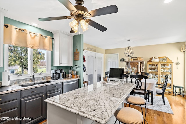 kitchen with light wood-type flooring, stainless steel dishwasher, gray cabinetry, sink, and a center island