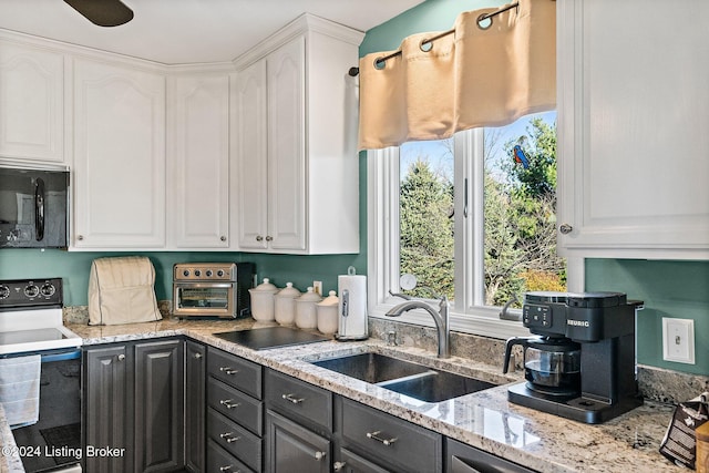 kitchen with light stone counters, sink, white cabinets, and white electric stove