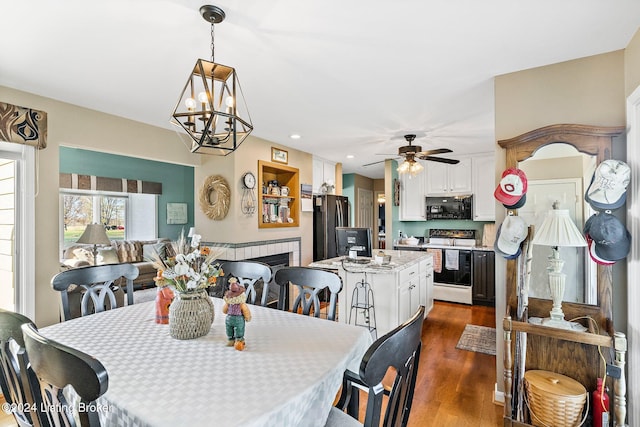 dining room featuring ceiling fan with notable chandelier and dark wood-type flooring