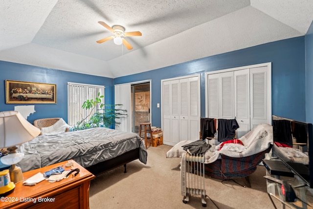 bedroom with light carpet, vaulted ceiling, ceiling fan, a textured ceiling, and multiple closets