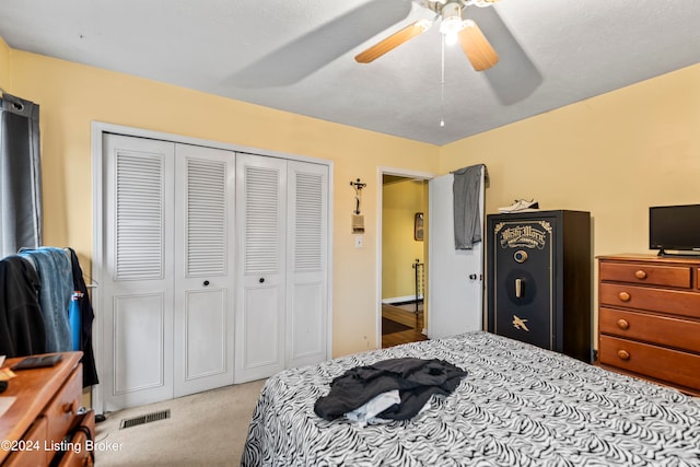 bedroom with ceiling fan, light colored carpet, a textured ceiling, and a closet