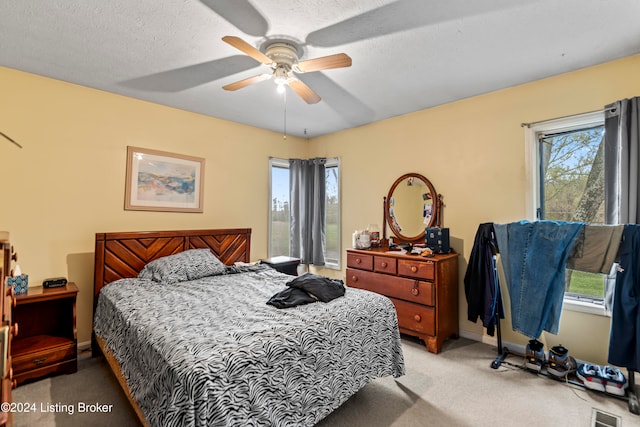 bedroom featuring a textured ceiling, ceiling fan, and light carpet