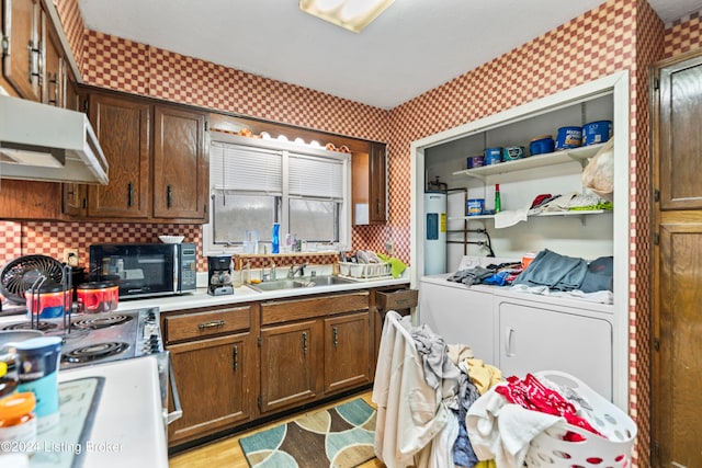 kitchen with washing machine and clothes dryer, sink, tasteful backsplash, water heater, and light hardwood / wood-style flooring