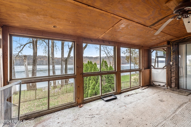 unfurnished sunroom featuring a water view, vaulted ceiling, and ceiling fan