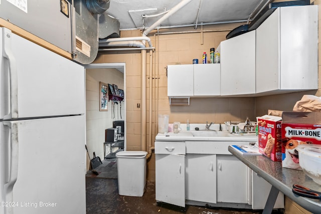 kitchen featuring white refrigerator, white cabinetry, and sink