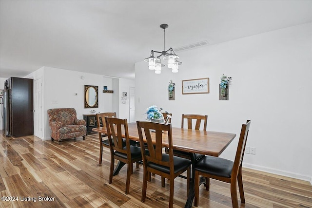 dining room with hardwood / wood-style floors and a notable chandelier