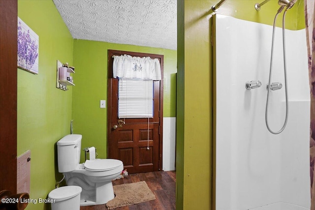 bathroom with hardwood / wood-style flooring, toilet, a textured ceiling, and walk in shower