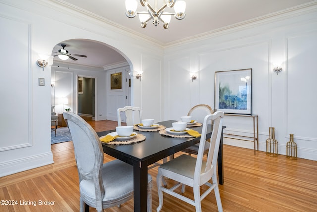 dining room with ornamental molding, ceiling fan with notable chandelier, and light wood-type flooring