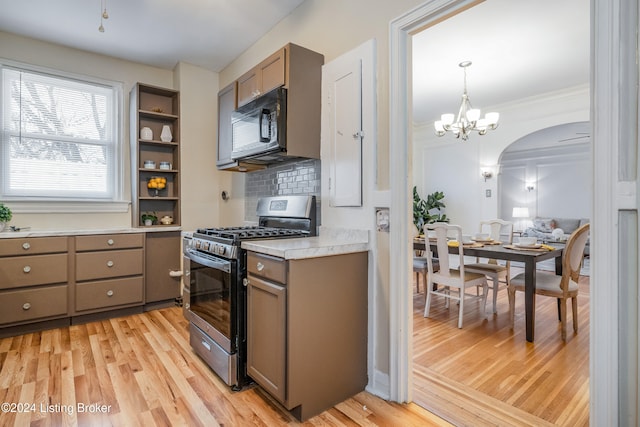 kitchen featuring light wood-type flooring, pendant lighting, stainless steel gas stove, and tasteful backsplash