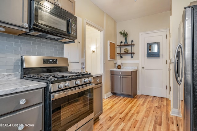 kitchen with light wood-type flooring, stainless steel appliances, and tasteful backsplash