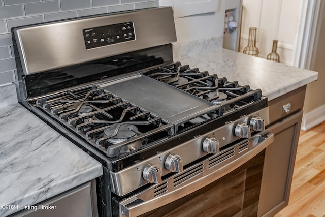 details featuring gas range, tasteful backsplash, and wood-type flooring