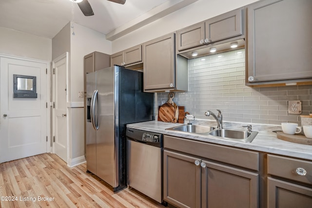 kitchen with decorative backsplash, appliances with stainless steel finishes, sink, light hardwood / wood-style flooring, and gray cabinets