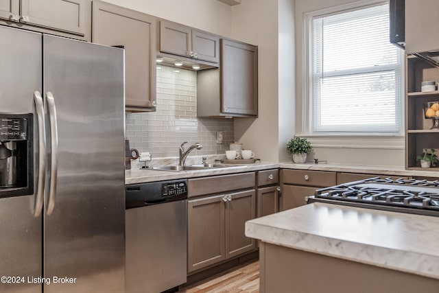 kitchen featuring appliances with stainless steel finishes, tasteful backsplash, light hardwood / wood-style flooring, and sink