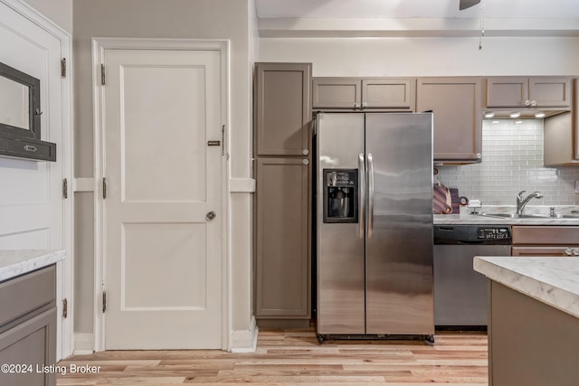 kitchen featuring gray cabinetry, sink, tasteful backsplash, light hardwood / wood-style floors, and stainless steel appliances