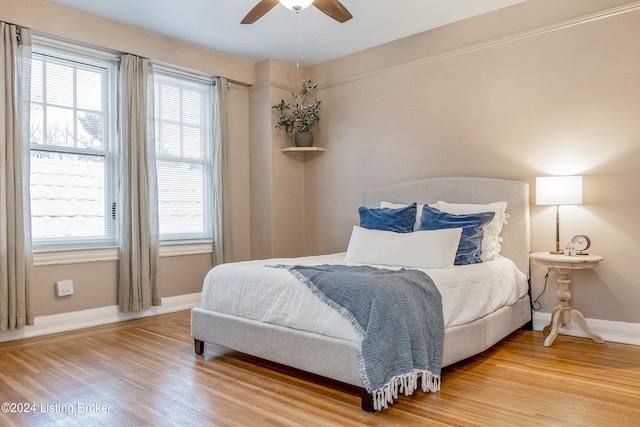 bedroom with multiple windows, ceiling fan, and hardwood / wood-style flooring