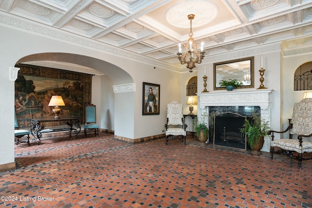 living room featuring coffered ceiling, a premium fireplace, beamed ceiling, crown molding, and a chandelier