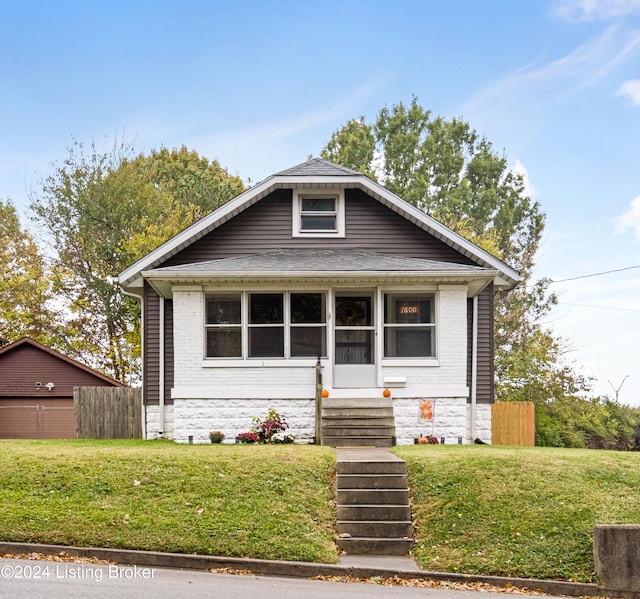 bungalow-style home featuring a garage, an outbuilding, and a front lawn