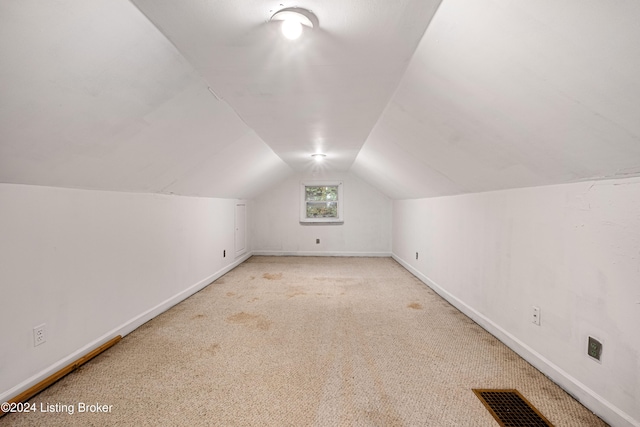 additional living space featuring lofted ceiling and light carpet