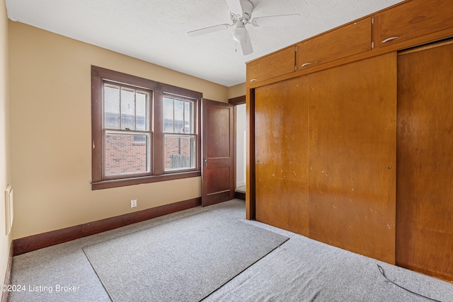 unfurnished bedroom with a closet, light carpet, ceiling fan, and a textured ceiling