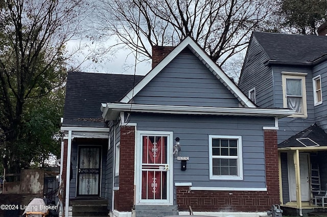 view of front of property with brick siding, entry steps, and a chimney