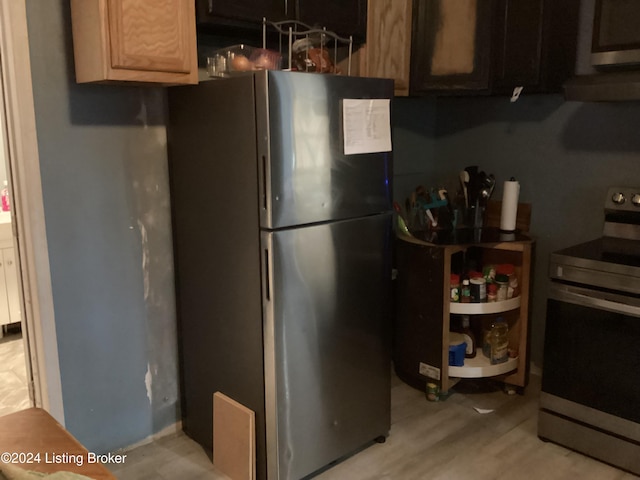 kitchen with appliances with stainless steel finishes, light hardwood / wood-style floors, and dark brown cabinets