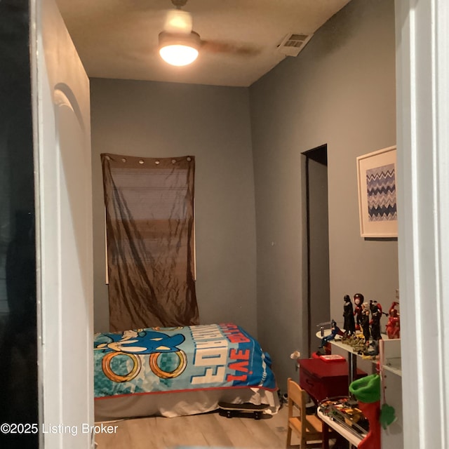 bedroom with wood finished floors, ceiling fan, and visible vents