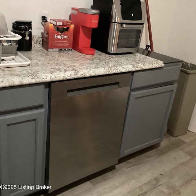 kitchen featuring gray cabinets, stainless steel dishwasher, light countertops, and light wood-style flooring
