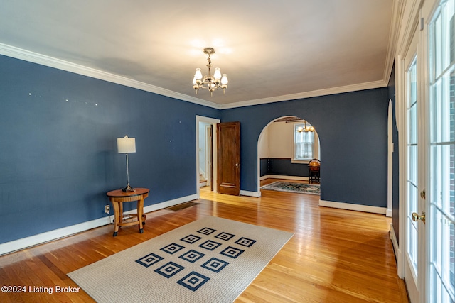 interior space with an inviting chandelier, wood-type flooring, and ornamental molding