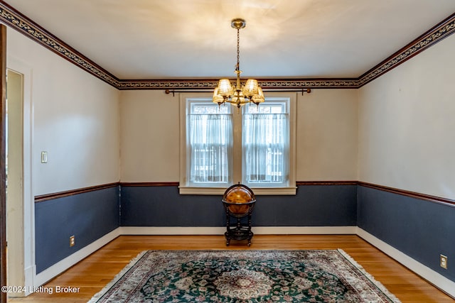 dining room with wood-type flooring, an inviting chandelier, and ornamental molding